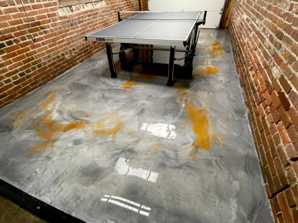 Metallic epoxy floor against exposed brick, poured and worked by hand